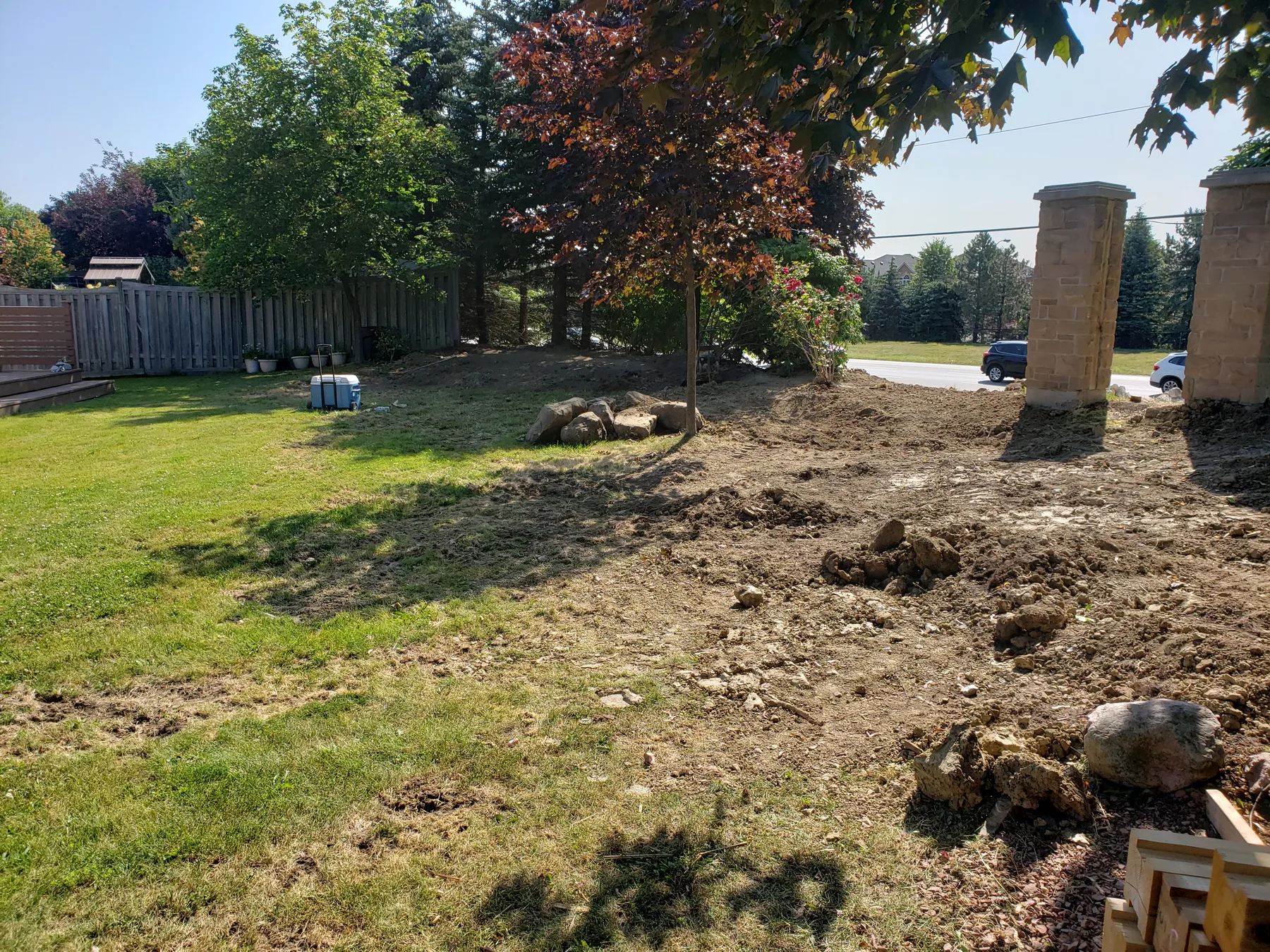 Residential yard prepared for a perimeter fence around existing stone pillars