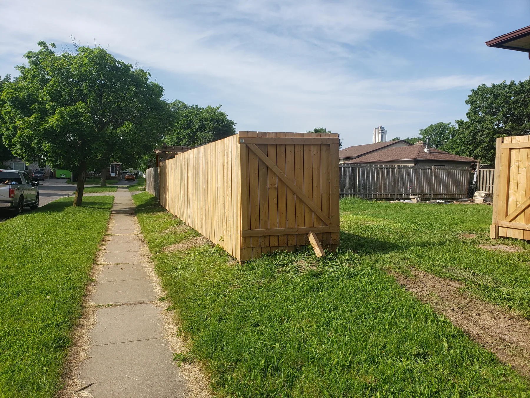 Completed cedar fence and access gate beside a sidewalk