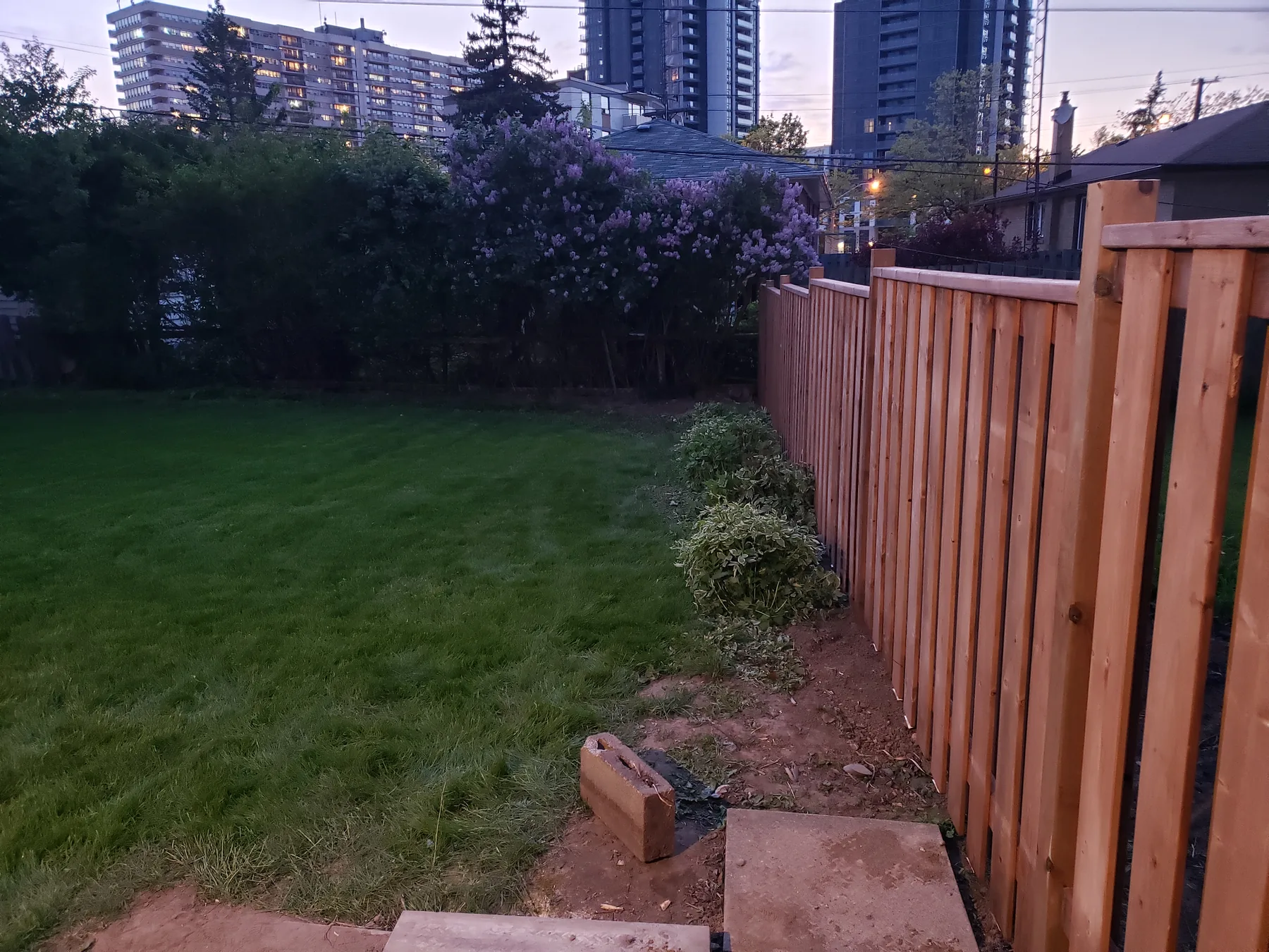 Completed shadow-box fence without lattice enclosing a landscaped backyard