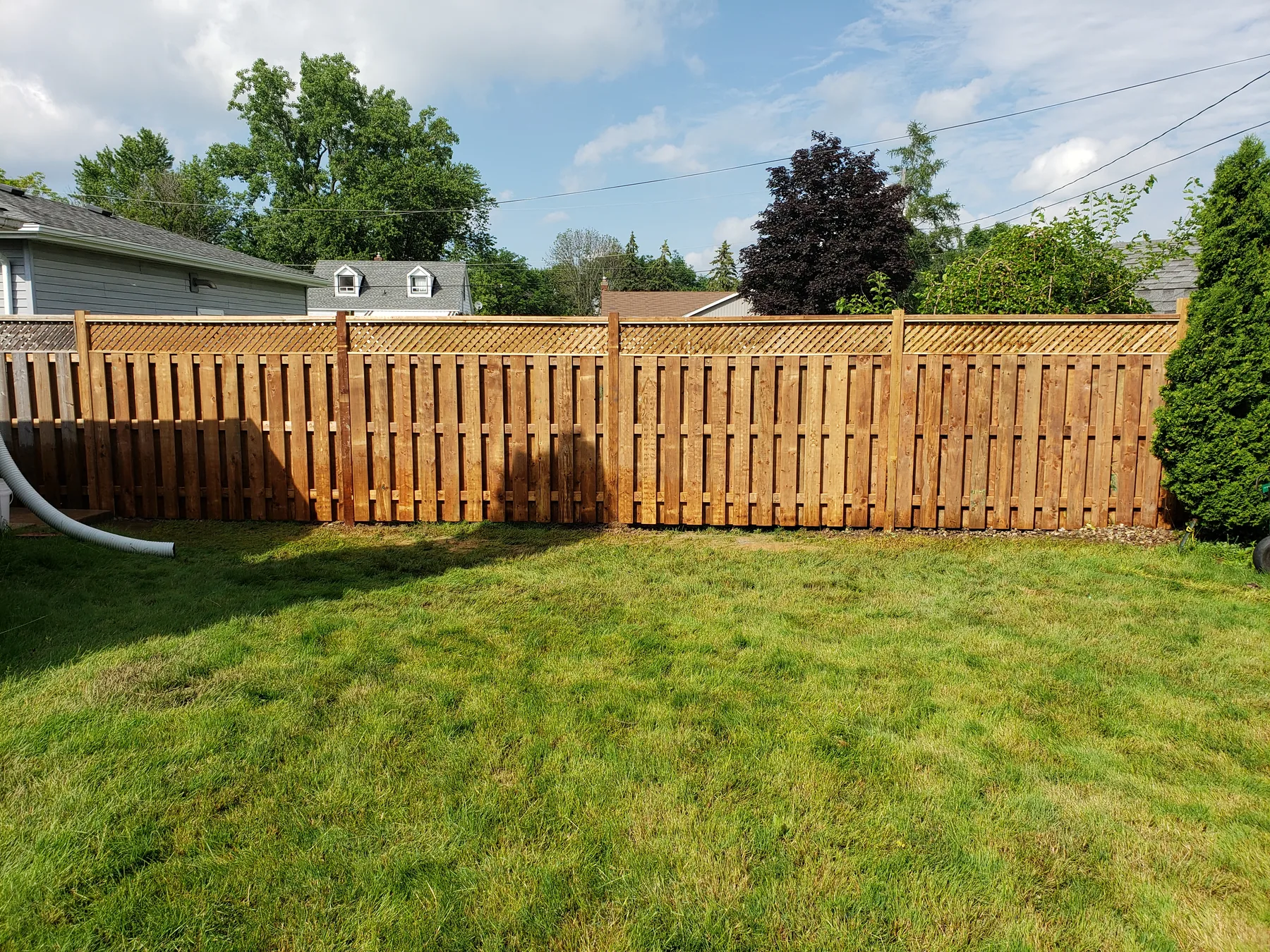 Completed lattice-top cedar fence across a backyard