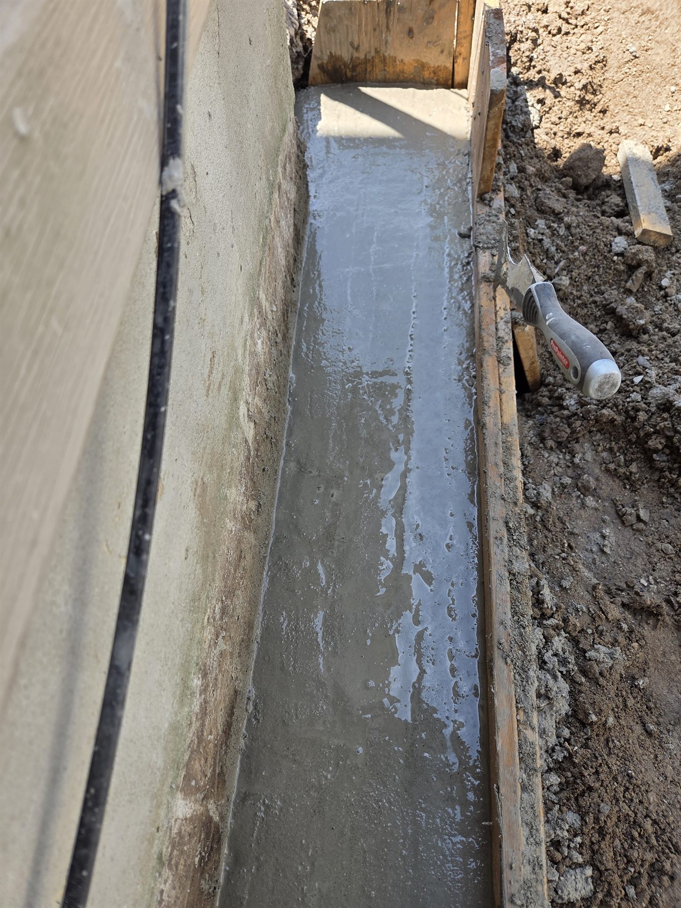 Finished concrete footing in the excavated foundation repair area
