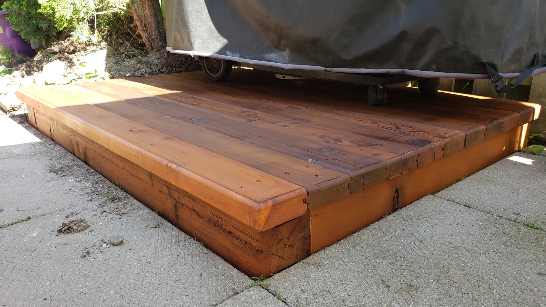 Completed low cedar platform supporting a covered backyard grill