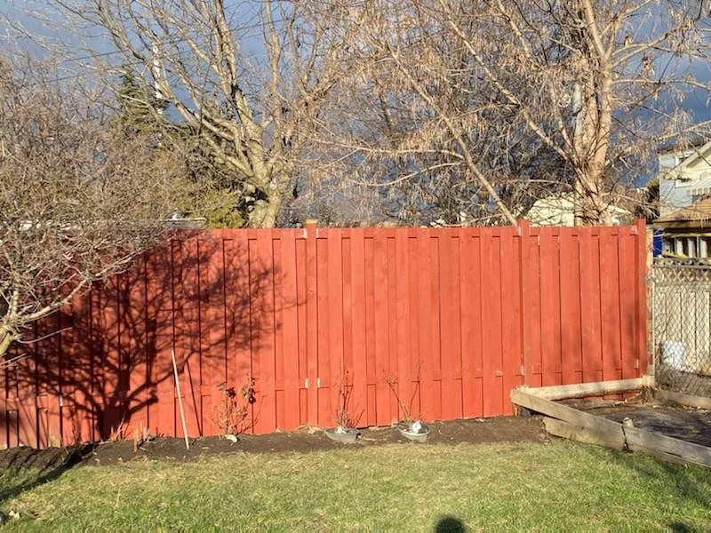 Completed red-stained backyard privacy fence
