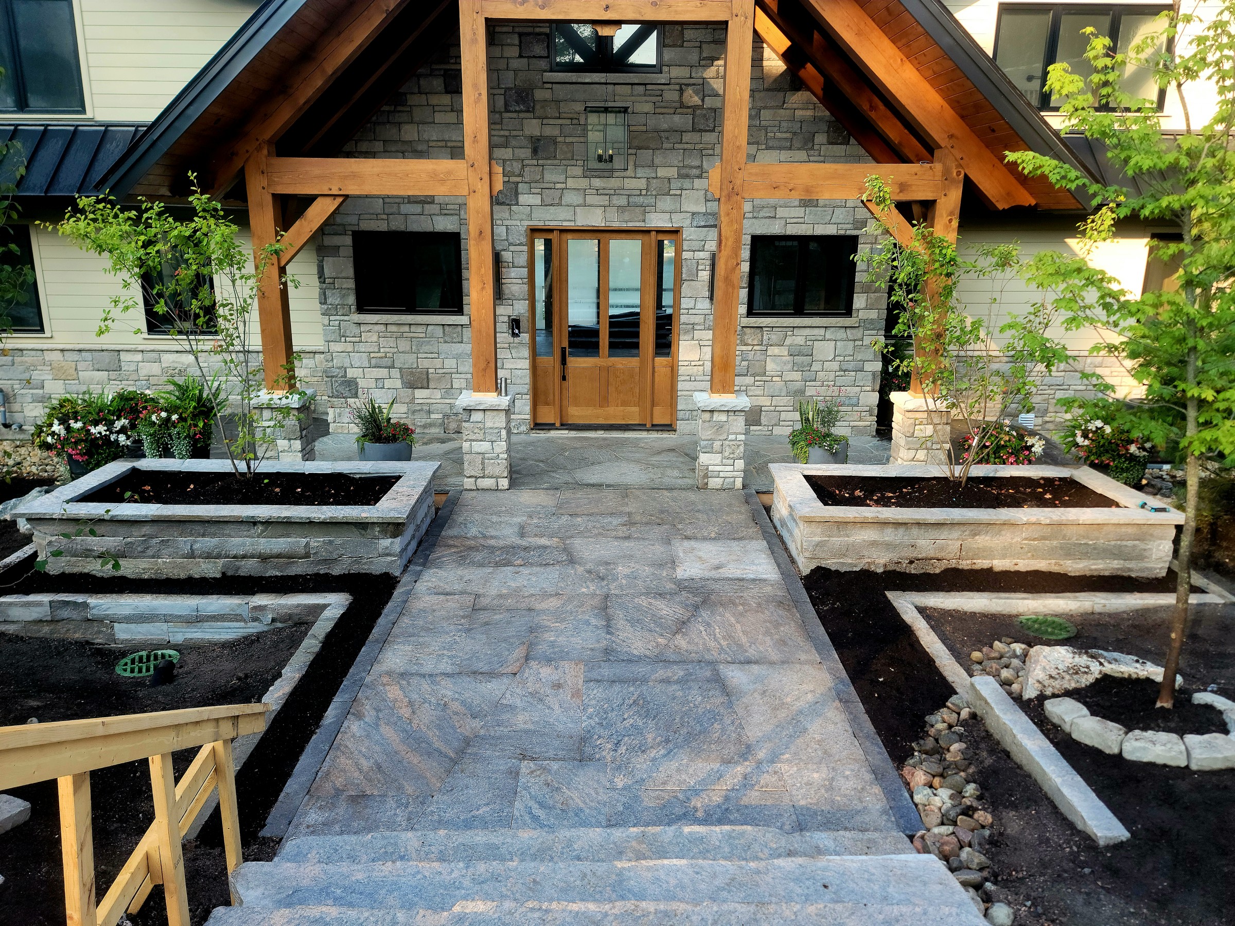 Completed front entry stone walkway, steps, and paired raised planters