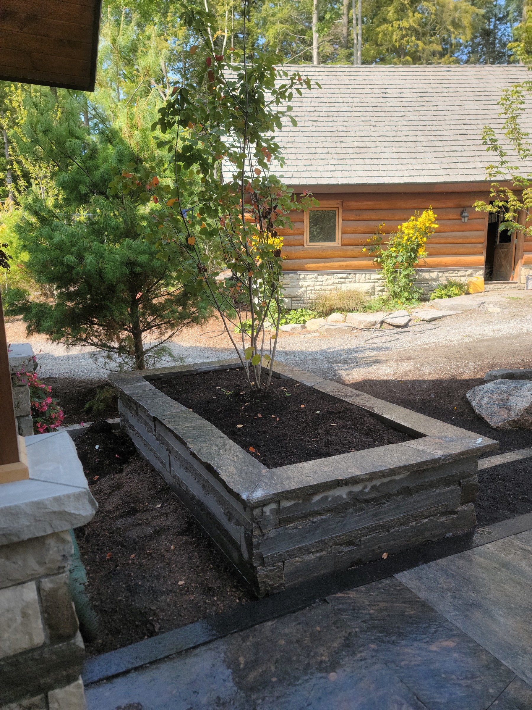 Completed raised stone planter beside the front parking approach