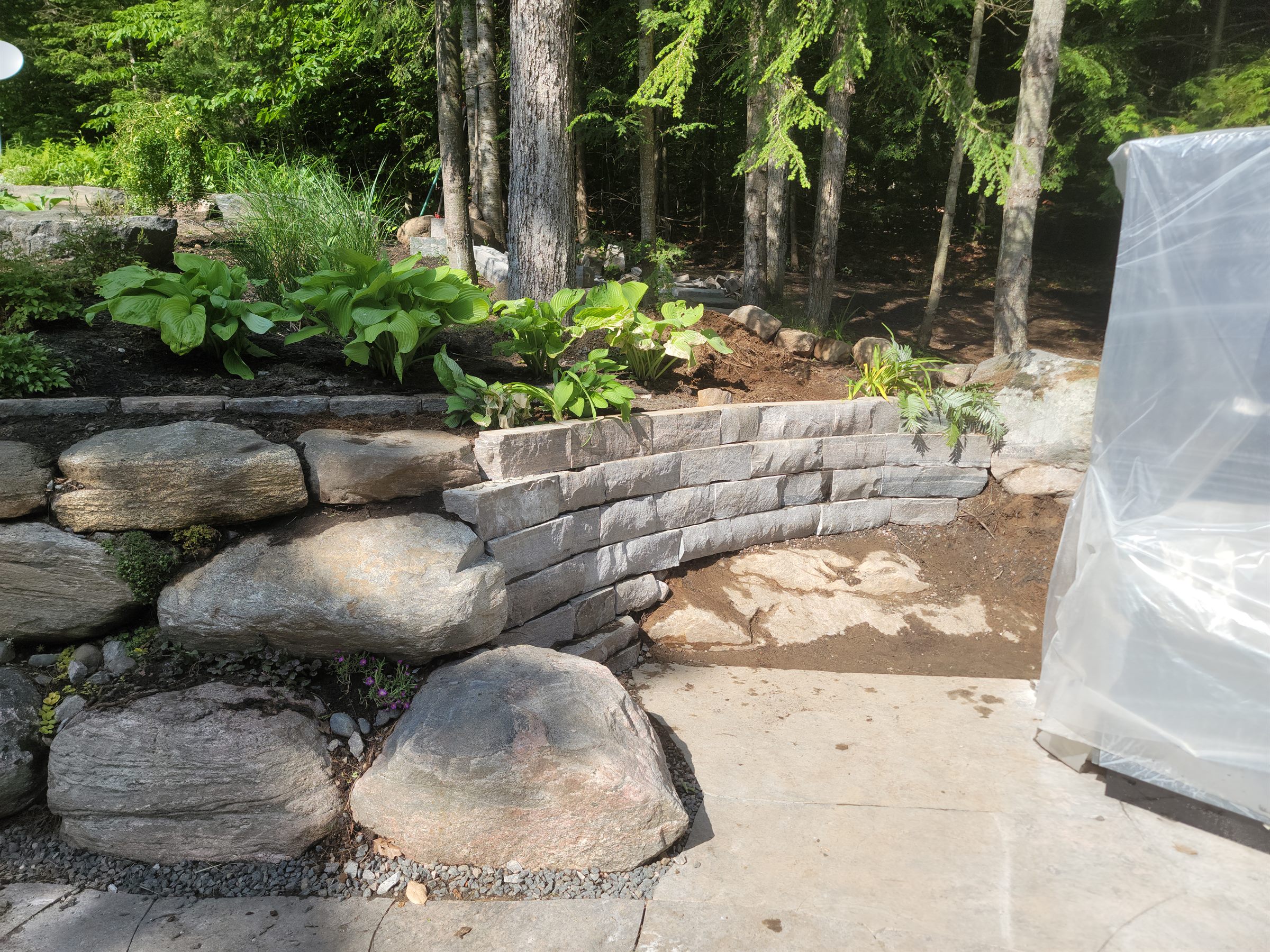 Wide view of the garden retaining wall under construction beside the patio