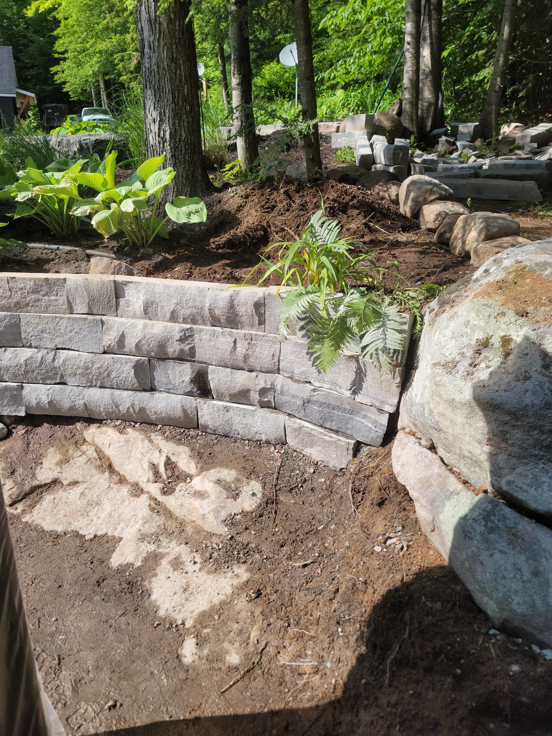 Curved garden retaining wall during stonework progress
