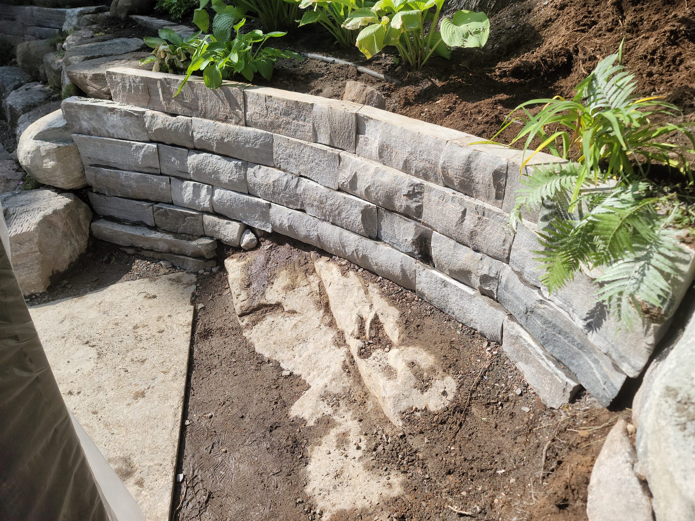 Curved natural-stone retaining wall progressing around the garden