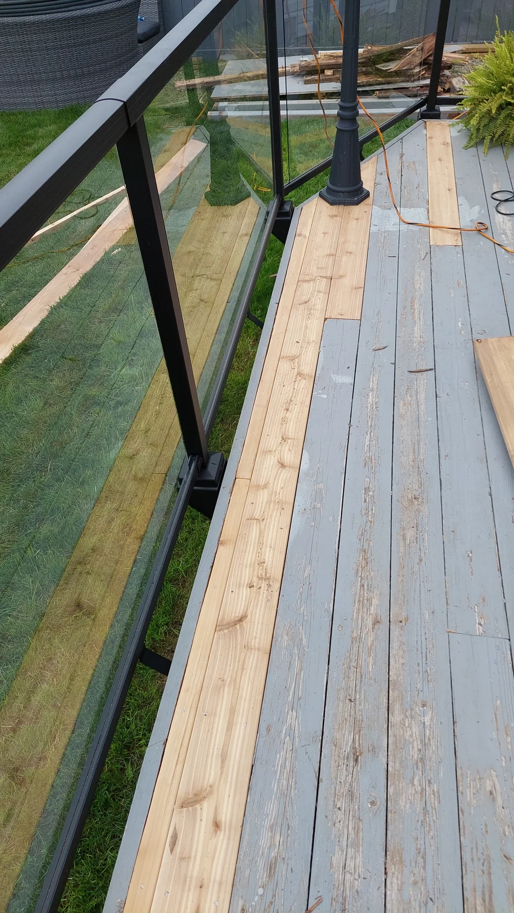 Targeted deck-board renewal in progress beside a glass railing