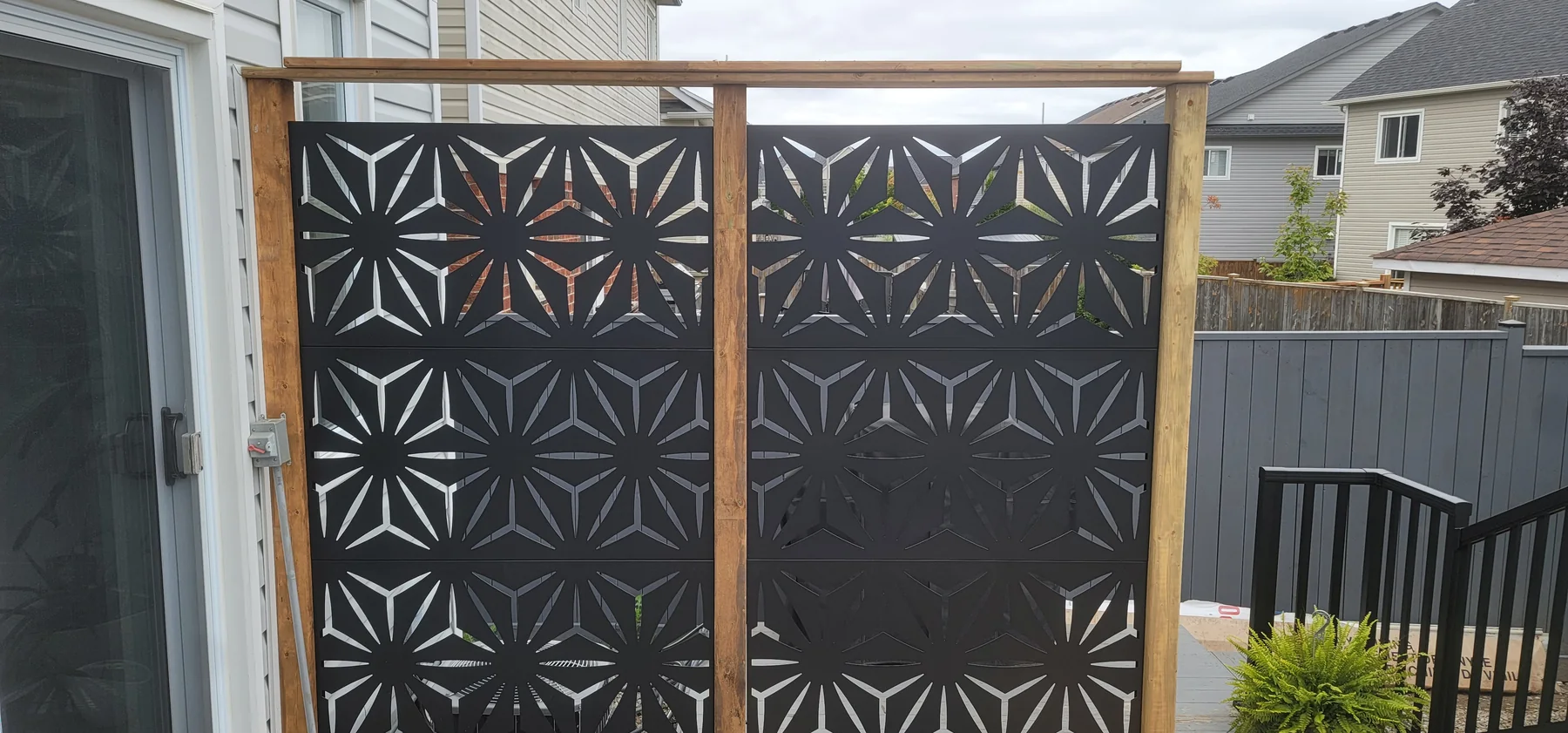 Completed framed black patterned privacy screen beside the deck