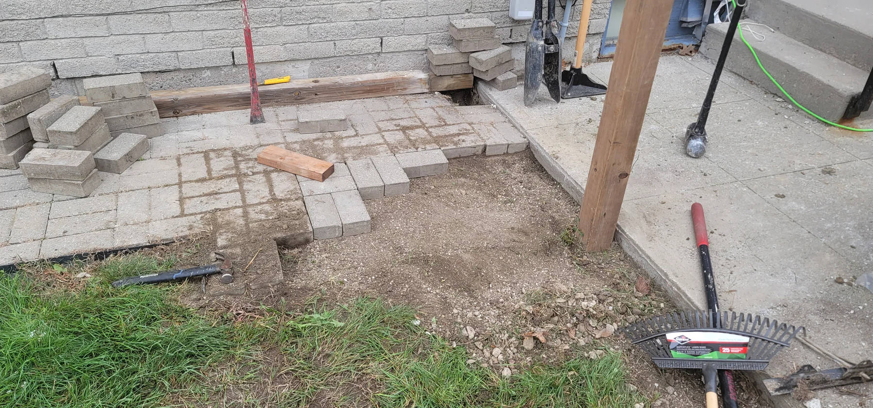 Paver walkway opened for new fence-post work beside a residential entrance