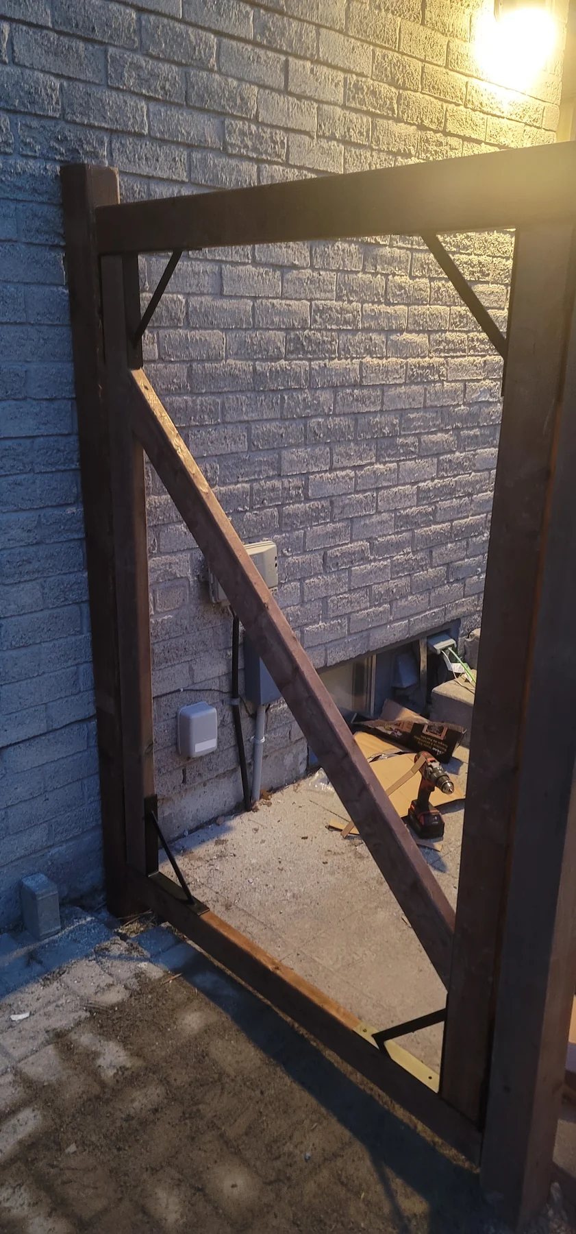 Reinforced wood gate frame during construction beside a brick home