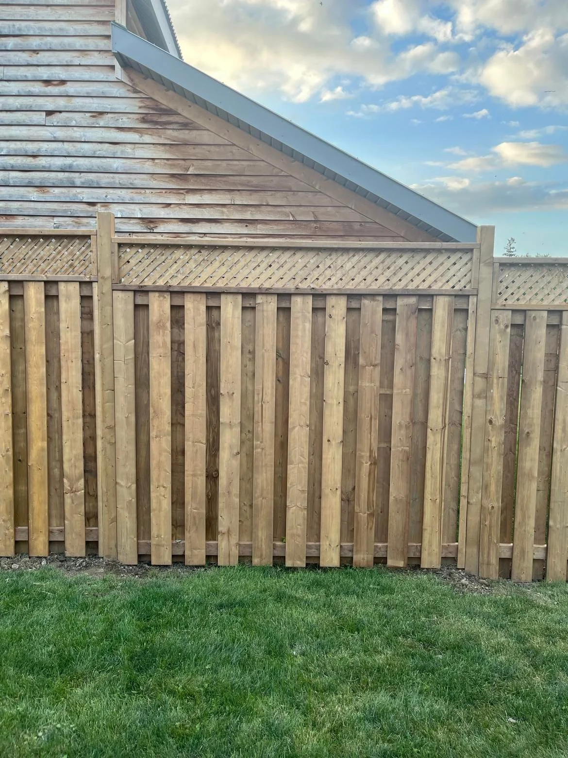 Completed vertical-board fence with decorative lattice along the garden edge
